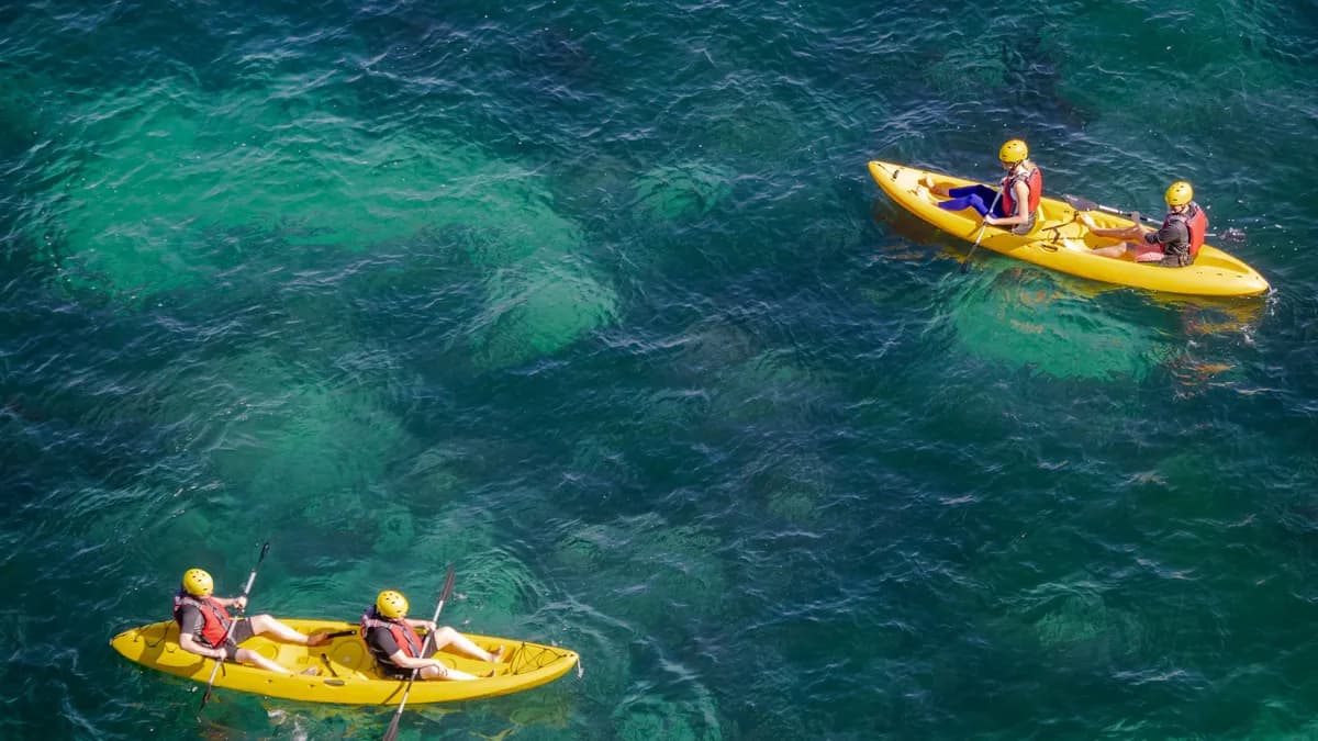 Aerial shot of people kayaking on clear turquoise water, enjoying a sunny day outdoors.
